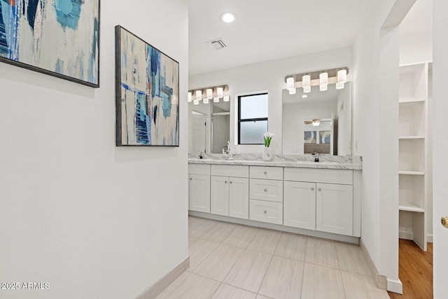 full bath with double vanity, a ceiling fan, visible vents, and baseboards