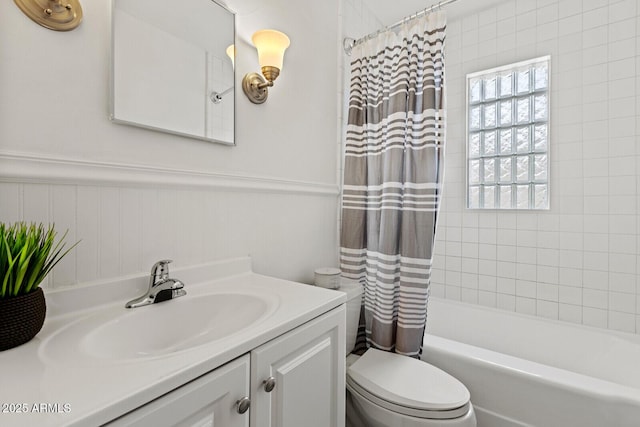 full bathroom with vanity, shower / tub combo, toilet, and wainscoting