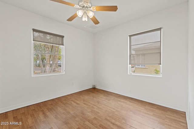 empty room featuring ceiling fan, baseboards, and wood finished floors