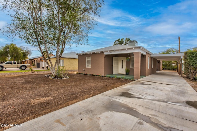 view of front of property with concrete driveway, a carport, and central AC