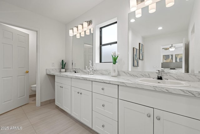 bathroom with a sink, a ceiling fan, toilet, and double vanity