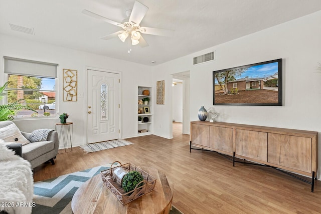 living area featuring visible vents, ceiling fan, and wood finished floors