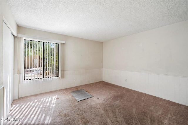 carpeted spare room with a textured ceiling