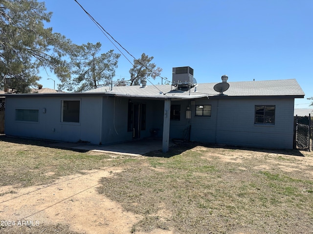 rear view of property featuring a lawn, cooling unit, and a patio area