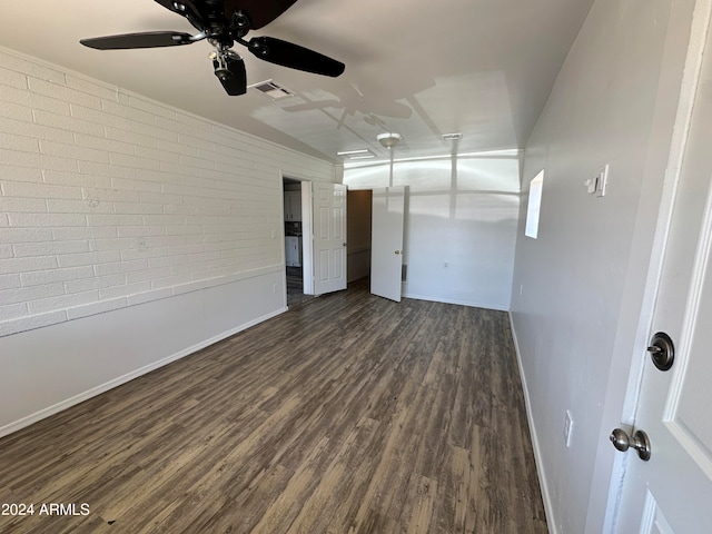 unfurnished room featuring brick wall, dark hardwood / wood-style floors, and ceiling fan