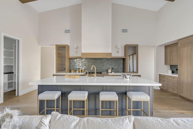 kitchen with a large island, a kitchen breakfast bar, light hardwood / wood-style floors, and high vaulted ceiling