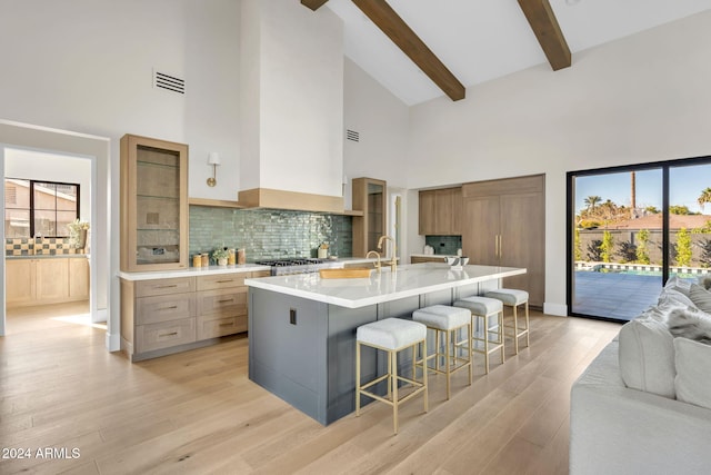 kitchen featuring a kitchen breakfast bar, a large island with sink, light hardwood / wood-style flooring, and a healthy amount of sunlight