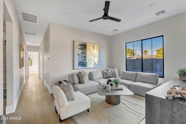 living room featuring light wood-type flooring, plenty of natural light, and ceiling fan