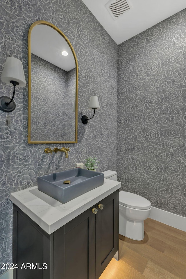 bathroom featuring wood-type flooring, vanity, and toilet