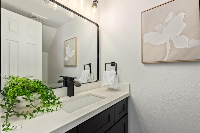 bathroom featuring a textured wall, visible vents, and vanity