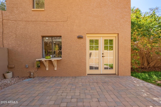 property entrance with french doors, a patio, and stucco siding