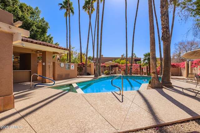 view of pool featuring a patio area, fence, and a pool with connected hot tub