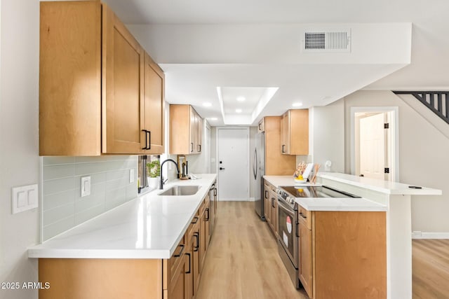 kitchen featuring stainless steel appliances, light wood-type flooring, a sink, and visible vents