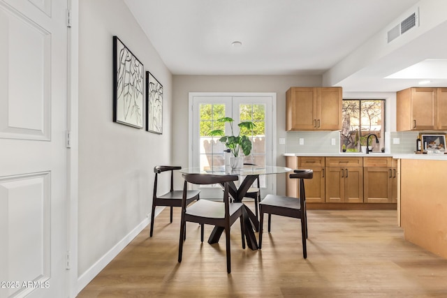 dining area with light wood finished floors, visible vents, and baseboards