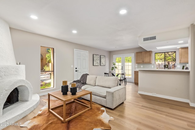 living area featuring recessed lighting, visible vents, baseboards, light wood-style floors, and french doors