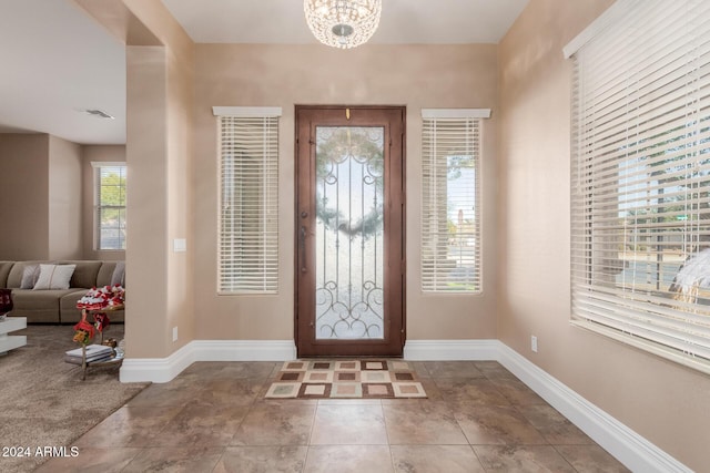 foyer entrance with tile patterned floors and an inviting chandelier