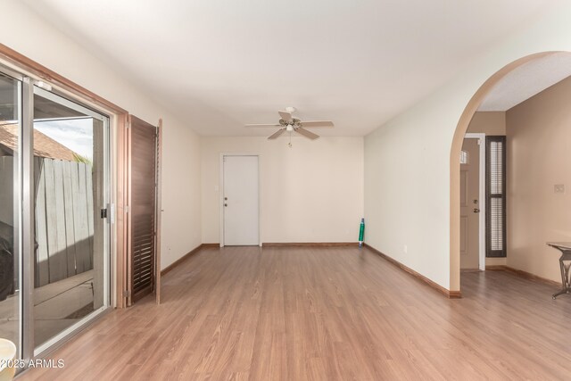 4024 W Griswold Rd, Phoenix, AZ 85051 - empty room with arched walkways, light wood-style floors, ceiling fan, and baseboards
