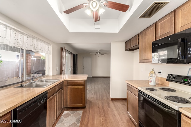 4024 W Griswold Rd, Phoenix, AZ 85051 - kitchen featuring black appliances, a ceiling fan, a tray ceiling, a sink, and light wood-style flooring