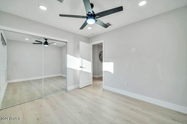 unfurnished bedroom with light hardwood / wood-style floors, a closet, and ceiling fan