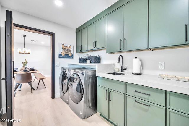 washroom featuring light hardwood / wood-style flooring, independent washer and dryer, sink, a notable chandelier, and cabinets