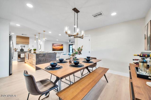 dining space featuring light hardwood / wood-style flooring and ceiling fan with notable chandelier