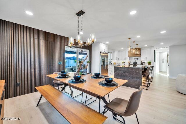 dining area featuring wood walls, a chandelier, and light wood-type flooring