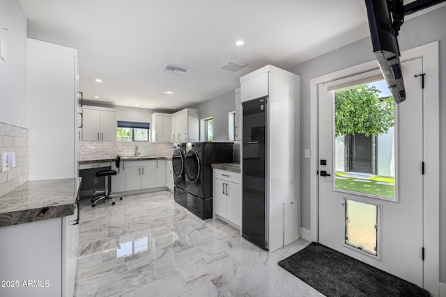 5404 N 41st St, Phoenix, AZ 85018 - kitchen featuring washing machine and dryer, decorative backsplash, a sink, light marble finish floors, and white cabinetry