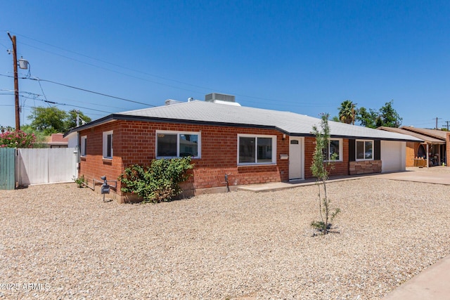 1028 W 5th St, Mesa, AZ 85201 - view of front of house featuring a garage, central AC unit, a shingled roof, brick siding, and driveway