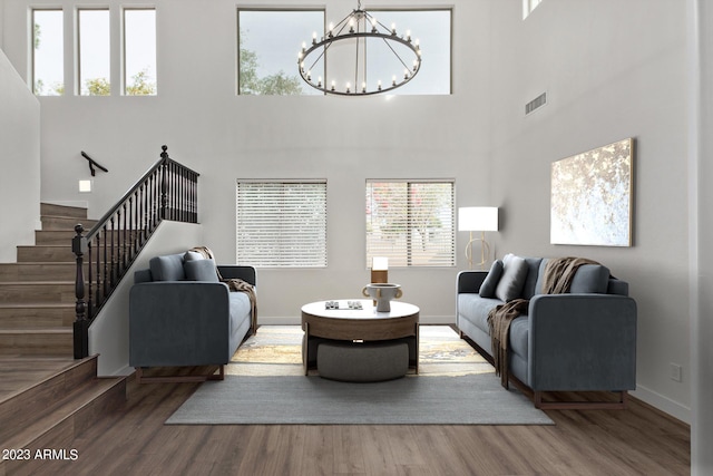 living room with hardwood / wood-style floors, a high ceiling, and an inviting chandelier