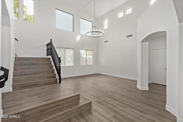 stairway featuring hardwood / wood-style flooring, a notable chandelier, and a towering ceiling