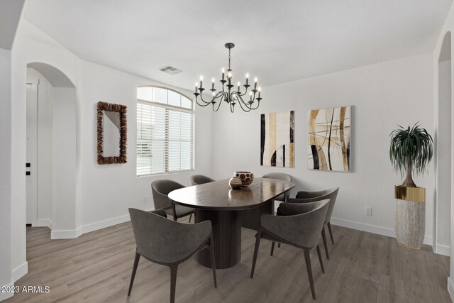 dining space featuring wood-type flooring and a chandelier