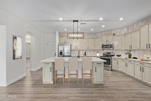 kitchen with a breakfast bar area, pendant lighting, an island with sink, and stainless steel appliances