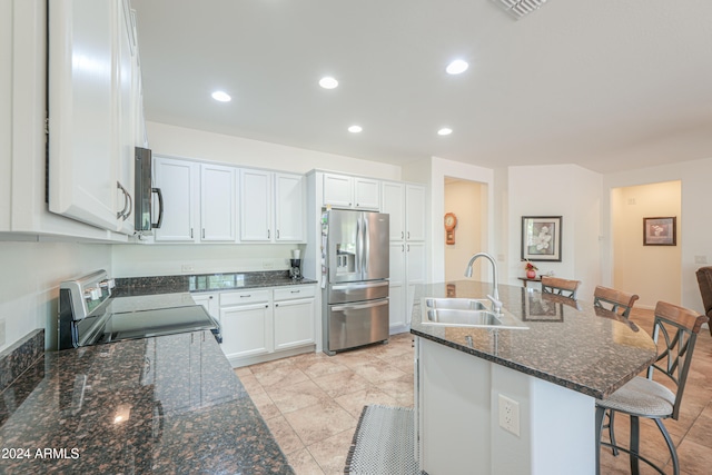 kitchen with a kitchen breakfast bar, an island with sink, stainless steel appliances, sink, and white cabinetry