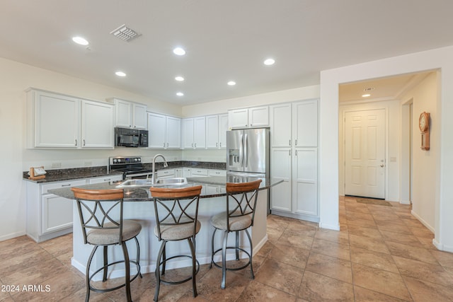 kitchen with sink, white cabinetry, stainless steel appliances, a breakfast bar, and a center island with sink