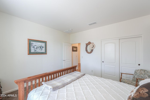 carpeted bedroom with visible vents, baseboards, and a closet