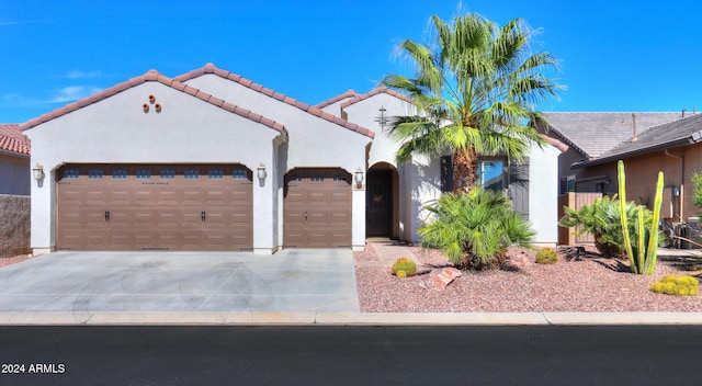 mediterranean / spanish house featuring driveway, a garage, stucco siding, and a tiled roof