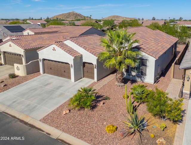 view of front of home with stucco siding, concrete driveway, a mountain view, and a tile roof
