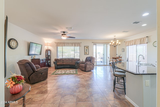 living room featuring sink and ceiling fan with notable chandelier