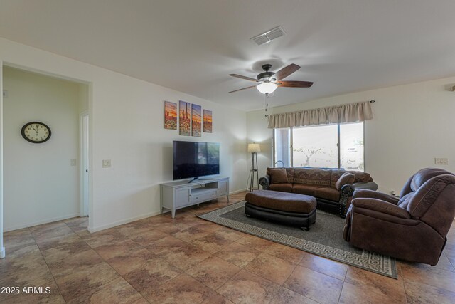living room featuring a ceiling fan, visible vents, stone finish floor, and baseboards