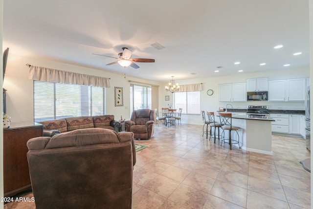 living room with ceiling fan with notable chandelier and light tile patterned floors