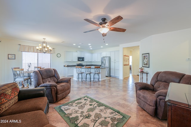 tiled living room with ceiling fan with notable chandelier