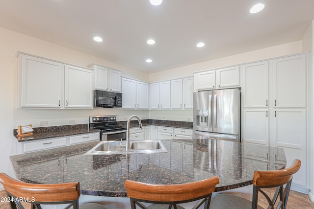 kitchen with sink, appliances with stainless steel finishes, a breakfast bar area, and white cabinetry