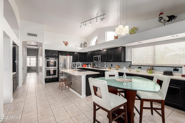 kitchen with a sink, dark cabinetry, stainless steel appliances, light tile patterned floors, and visible vents
