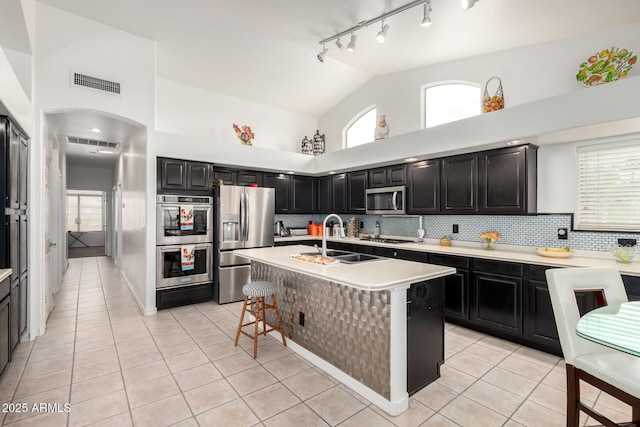 kitchen featuring a sink, stainless steel appliances, light tile patterned floors, visible vents, and dark cabinets