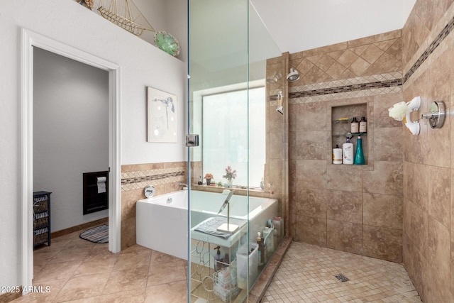 bathroom featuring a freestanding tub, tile patterned floors, and tiled shower