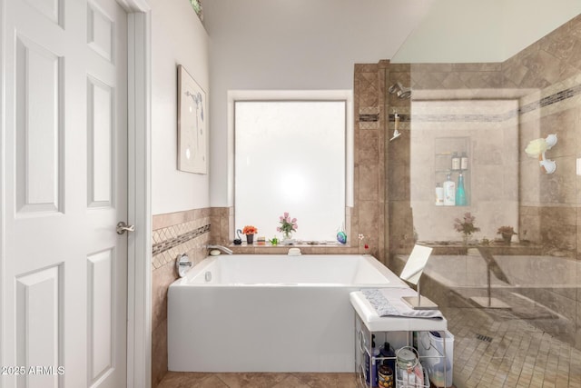 bathroom featuring a bath, tile walls, and walk in shower