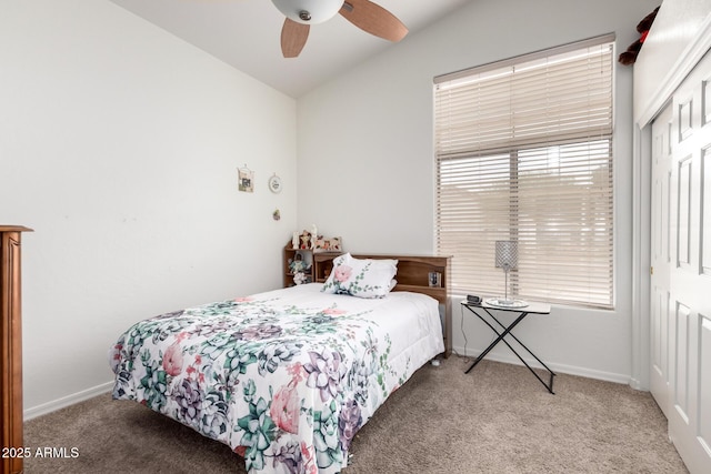 carpeted bedroom with baseboards, a closet, vaulted ceiling, and ceiling fan