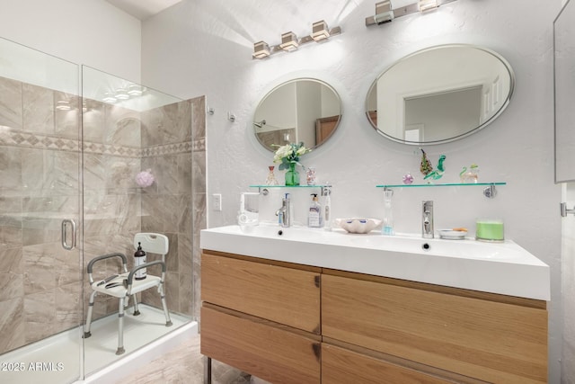 bathroom with a stall shower, double vanity, and a sink