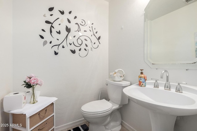 half bathroom featuring toilet, a sink, and baseboards