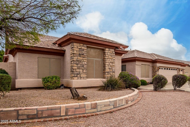 prairie-style house with concrete driveway, stucco siding, stone siding, a tiled roof, and a garage
